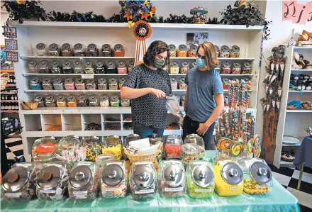  ?? LIDO VIZZUTTI/THE NEW YORK TIMES ?? Dallas Gray, left, and Duncan Stoddard shop at Big Sky Candy, which does not require masks, in Hamilton, Montana.