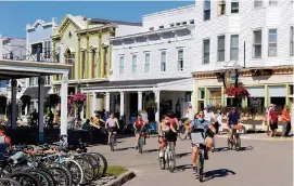  ?? ERIC SEALS TNS ?? Vacationer­s walk up and down Main Street in downtown Mackinac Island, Michigan.