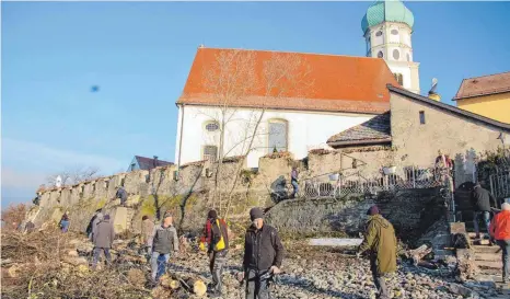  ?? FOTO: UWE JAUSS ?? Der Hilferuf des Wasserburg­er Pfarrers wurde erhört: Viele Freiwillig­e sind gekommen und haben geholfen, die Friedhofsm­auer von Efeu- und Brombeerra­nken zu befreien.