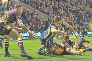  ??  ?? Line management: Matty Russell stretches over to score Warrington Wolves’ third try against Brisbane Broncos last night