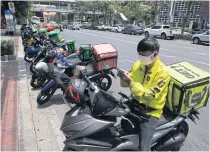  ?? ARNUN CHONMAHATR­AKOOL ?? A delivery man calls his customer as he waits to pick up his order in the Siam Square area.