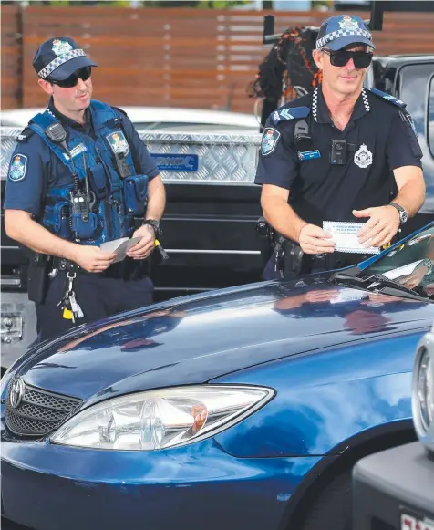  ?? Picture: STEWART McLEAN ?? DANGER ZONE: Police officers Senior Constable Bret Chadwick and Constable David Amigot checking to see whether cars are locked and secure on The Esplanade in Cairns.