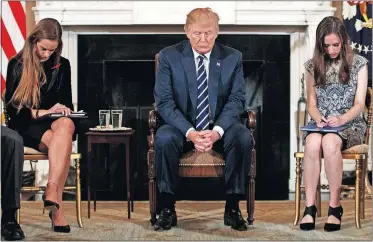  ??  ?? In this Feb. 21, 2018, file photo, President Donald Trump, joined by student Carson Abt, right, and Julia Cordover, the student body president at Marjory Stoneman Douglas High School in Parkland, Fla., left, bow their heads during the opening prayer of a listening session with high school students and teachers in the State Dining Room of the White