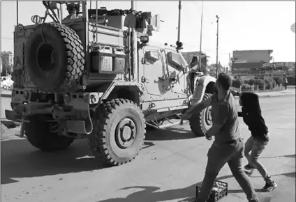  ?? ANHA VIA AP ?? In this frame grab from video provided by Hawar News, ANHA, the Kurdish news agency, residents who are angry over the U.S. withdrawal from Syria hurl potatoes at American military vehicles in the town of Qamishli, northern Syria, on Monday.