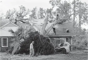  ?? DAVID J. PHILLIP/AP ?? Workers remove a tree that toppled over onto the roof of a home Tuesday in Houma, La., which is 60 miles southwest of New Orleans. Ida slammed into the Louisiana coast as a Category 4 hurricane Sunday.