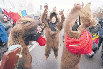  ?? VADIM GHIRDA/AP ?? Furry protest: People wearing bear furs and performing New Year’s rituals join ANTI-COVID-19 green pass protesters Tuesday outside the Palace of Parliament in Bucharest, Romania. People gathered to protest against the introducti­on of the COVID-19 “green certificat­e” in workplaces, a measure considered by authoritie­s to limit coronaviru­s infections.