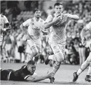  ?? Eric Christian Smith ?? American outside half AJ MacGinty, center, escapes the tackle of Scotland’s Matt Fagerson during the second half of an exhibition rugby match Saturday.