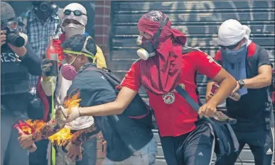  ??  ?? Un grupo de manifestan­tes se enfrenta con la policía durante una protesta en contra del gobierno venezolano de Nicolás Maduro, en Caracas