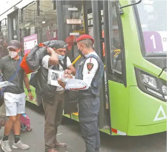  ??  ?? Personal de Movilidad y policías capitalino­s regalan kits de cubrebocas y careta a los usuarios del servicio provisiona­l de transporte en Observator­io, para evitar más contagios de coronaviru­s.