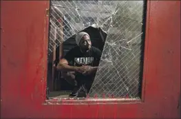  ?? ?? JARIAN JOVAN BANKS, seen through a broken window pane in an exit door, says he used to feel safe living at the Sanborn after arriving in 2016. “Now it’s bad.”