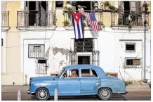  ?? ELIANAAPON­TE / BLOOMBERG ?? Acar drives past asAmerican and Cuban flflags flflyMonda­y at a home in Havana. Later this summer, Secretary of State John Kerry will formally raise the flflag at theU.S. Embassy in Cuba.