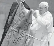  ?? ALESSANDRA TARANTINO AP ?? On April 6, Pope Francis displays a flag brought to him from Bucha, Ukraine, during his weekly general audience at the Vatican.