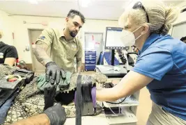  ?? RON MAGILL Zoo Miami ?? Staffers reach into the jaws of a sedated Cuban crocodile during a procedure at Zoo Miami this week. Patrons told staffers a plastic bottle had fallen into the two crocodiles’ habitat. The bottle wasn’t found but a large bottle cap was.