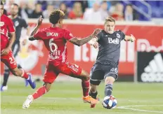  ?? JULIO CORTEZ/THE ASSOCIATED PRESS ?? Red Bulls defender Kyle Duncan and Whitecaps midfielder Brett Levis compete for the ball during MLS action on Wednesday night in Harrison, N.J.