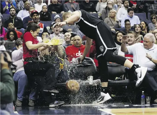  ?? Alex Brandon
/theasociat­ed pres ?? Waitress Delia Barr loses a tray of beer as Brooklyn Nets centre Mason Plumlee runs into her chasing the ball
in the first half of an NBA game against the Washington Wizards on Saturday in Washington.