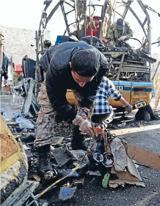  ?? Photo: REUTERS ?? Gathering evidence: A Syrian soldier sorts through debris following a bomb explosion on a bus. The suicide attack was said to have links with al Qaeda’s Nusra Front.