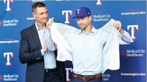  ?? (Tom Fox/the Dallas Morning NEWS/TNS) ?? New Texas Rangers starting pitcher Jacob degrom tries on his new jersey with the assistance of general manager Chris Young Dec. 8, 2022 during his introducto­ry press conference at Globe Life Field in Arlington, Texas. Degrom signed a five-year contract until the year 2027.