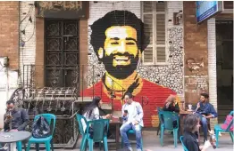  ?? AFP ?? People sitting at a cafe in Cairo with a mural depicting Egyptian striker Mohamed Salah in the background. —