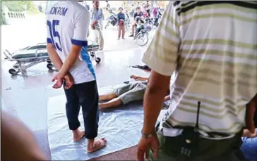  ?? HONG MENEA ?? People gather around the body of Seak Ron, a bystander who was shot to death during a police raid on a cockfighti­ng ring.