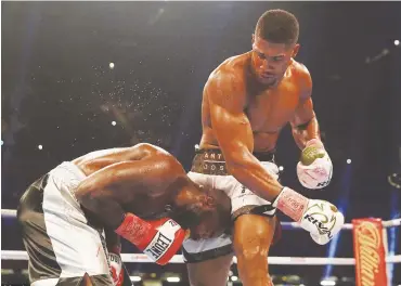  ??  ?? Anthony Joshua towers over Carlos Takam after raining down a barrage of punishment on him in the middle rounds during their fight on Saturday