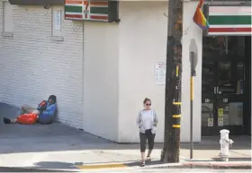  ?? Paul Chinn / The Chronicle ?? A man sits on the sidewalk next to a 7-Eleven store at 18th and Noe streets in the Castro in San Francisco.