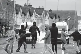  ?? CHARLES MCQUILLAN/GETTY ?? Amid a recent spate of violence, people attack police vehicles Thursday near gates dividing nationalis­t and loyalist communitie­s in Belfast, Northern Ireland.