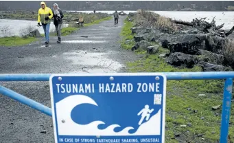  ?? CHAD HIPOLITO/THE CANADIAN PRESS ?? People walk along Whiffin Spit Park following a tsunami warning in Sooke, B.C., on Tuesday. Tsunami warning sirens went off in Tofino and other coastal communitie­s on B.C.’s west coast after a powerful earthquake struck off Alaska.