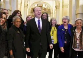  ?? AARON ONTIVEROZ/THE DENVER POST VIA AP, FILE ?? Colorado Governor elect Jared Polis, center, jokes with members of the state house and senate before his inaugurati­on at the Colorado State Capitol in Denver. Health care proposals are among the first actions for some new Democratic governors and Democratic­ally controlled legislatur­es. Expanding access to care was a rallying point for the party in the 2018 elections.