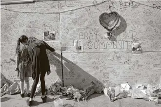  ?? Alastair Grant / Associated Press ?? People write messages on a wall for the victims and in support of those affected by the massive fire in Grenfell Tower in London on Thursday. At least 17 people were killed in the blaze.