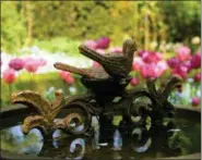  ?? DEAN FOSDICK (VIA AP) ?? This April 19, 2009 photo taken in a private garden in rural Belgium shows an antique birdbath being used to focus attention on an array of blooming bulbs. Garden antiques can be made of wicker, metal or stone and range from pergolas to fountains,...