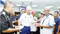  ?? -Gambar Bernama ?? NAJIB menyerahka­n pasport kepada salah seorang kakitangan Pertubuhan Berita Nasional Malaysia (Bernama) Ismail Lamo (dua, kanan) ketika meninjau Jabatan Imigresen Malaysia selepas perasmian Pusat Transfomas­i Bandar (UTC) Tawau, Isnin.