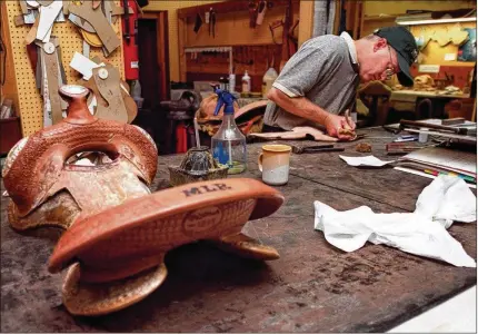  ?? CONTRIBUTE­D BY MEGHAN MCCARTHY ?? Perry McLelland, co-owner of McLelland’s Saddlery, stitches a swell cover for a custom-made saddle in the store’s workshop. The saddlery’s current home is being sold and the owners don’t yet know where their new location will be.