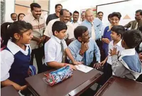  ?? [ FOTO MOHD AZREN JAMALUDIN / BH ] ?? Kamalanath­an beramah mesra dengan murid Tahun 1 ketika majlis perasmian Sekolah Jenis Kebangsaan (T) Bukit Serampang Indah, Johor Bahru.