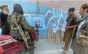  ?? /Reuters ?? Different way of life: Members of the Taliban gather in Kabul near a picture of their leader Mullah Haibatulla­h Akhundzada. A Taliban spokespers­on says a new government is being formed and is a matter of a few days away.