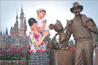  ?? GAO ERQIANG / CHINA DAILY ?? Visitors pose for a photograph next to the bronze statue of Walt Disney at Shanghai Disneyland on Friday. The resort, which is celebratin­g its first anniversar­y, has received more than 11 million visitors.