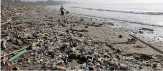  ?? - Reuters file photo ?? PLASTIC POLLUTION: A local resident walks along a section of Matahari Terbit beach covered in plastic and other debris washed ashore by seasonal winds near Sanur, Bali, Indonesia.