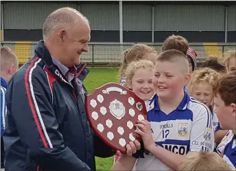  ??  ?? John Kenneally, Rebel Óg North, presenting the shield to Ben Cremin, captain of the victorious Killavulle­n team, that won the Under 12 B Football Final.