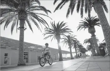  ?? Photograph­s by Christina House
For The Times ?? A BOY RIDES his bicycle through the Palm Courts Arts Complex at Irvine’s Great Park.