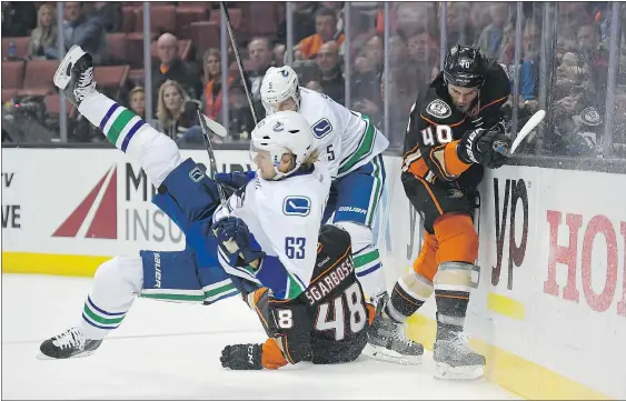  ?? — THE ASSOCIATED PRESS ?? Vancouver defenceman Philip Larsen, left, falls as Anaheim centre Michael Sgarbossa, below, and right-winger Jared Boll, right, battle for the puck with defenceman Luca Sbisa. The Canucks dropped a 4-2 road decision.