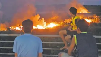  ?? ?? Tres jóvenes de la zona del banco San Miguel observan el fuego, desde la Avda. Costanera.