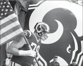  ?? Wally Skalij Los Angeles Times ?? ROB HAVENSTEIN, whose wife and infant daughter had to be evacuated from their Newbury Park home, carries a flag onto the field at the Coliseum.