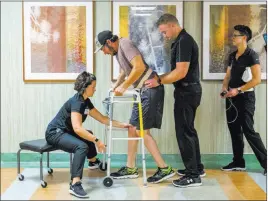  ?? Teresa Crawford ?? The Associated Press Jered Chinnock, a paralyzed 29-year-old, walks down a hallway with his therapy team at the Mayo Clinic in Rochester, Minn.