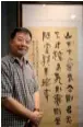  ?? PHOTOS LIU YINMENG / CHINA DAILY ?? Andrew Y Zhao, director of Sino-Asian Art Gallery, poses in front of his calligraph­y.
