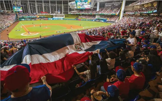  ?? SAUL MARTINEZ/NEW YORK TIMES ?? Fans unfurl the Dominican Republic flag during a game against Venezuela last week in a World Baseball Classic Pool D game at Miami. Venezuela upset the tournament favorites 5-1 before a sellout crowd of 35,890. Latin American baseball fans have been anticipati­ng this event since the 2017 edition.