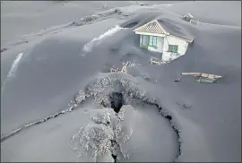  ?? PHOTOS BY EMILIO MORENATTI — THE ASSOCIATED PRESS ?? A fissure is visible next to a house covered with ash on the Canary island of La Palma, Spain, on Dec. 1. Authoritie­s are declaring a volcanic eruption officially finished.