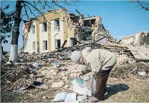  ?? ANADOLU / GETTY ?? Una anciana de la vila ucraïnesa de Bíxiv rescata llibres entre les runes d’una biblioteca destruïda als afores de la ciutat de Kíiv