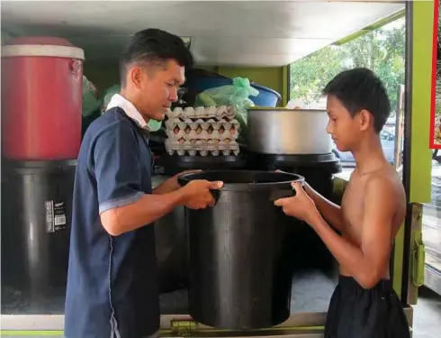  ??  ?? RASAIDI (kiri) bersama anaknya mengangkat air yang diambil dari pusat cuci kereta.