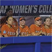  ?? AP PHOTO BY SUE OGROCKI ?? Texas softball players watch from the dugout in the final inning of their Women’s College World Series game against Oklahoma on Thursday night in Oklahoma City. Oklahoma won 10-5.