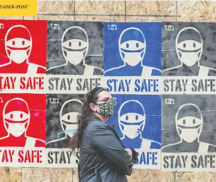  ?? PETER J THOMPSON / POSTMEDIA NEWS ?? A pedestrian wearing a mask walks along a postered wall on Queen Street in Toronto on Friday. The COVID-19 pandemic has changed many Canadians’ attitudes toward social distancing in a few short months, a new DART & Maru/blue poll indicates.