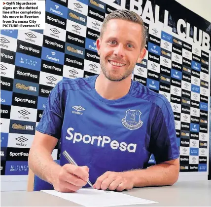  ??  ?? > Gylfi Sigurdsson signs on the dotted line after completing his move to Everton from Swansea City PICTURE: Everton FC